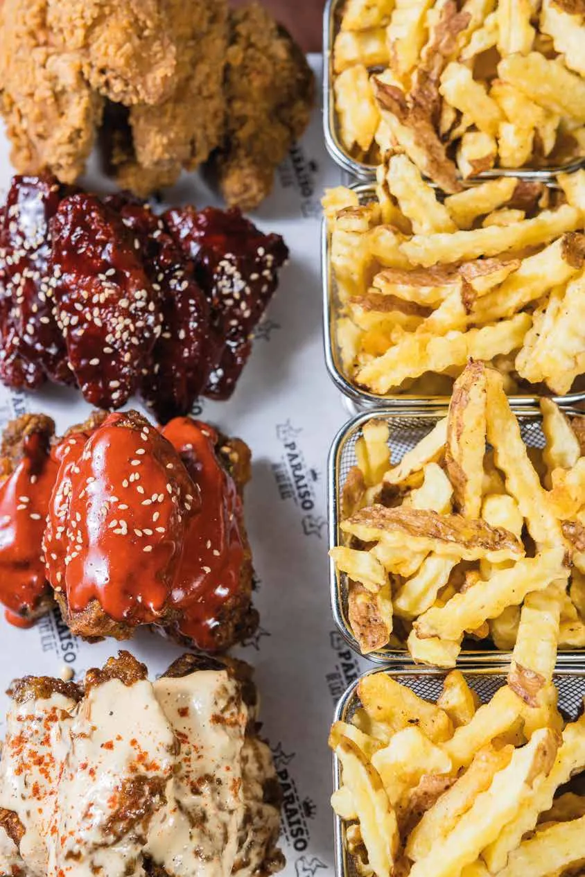 Alitas de varios sabores junto a canastillas de papas fritas